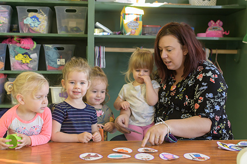 Early childhood educator with four children at a table with them.