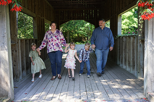 Parents walking in a covered bridge with three children.